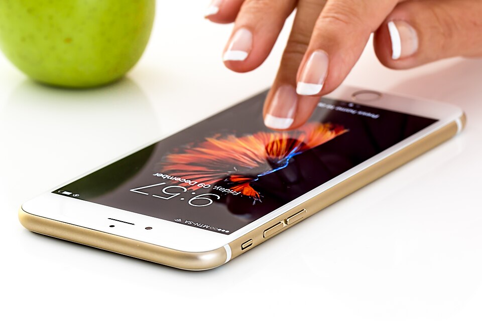 A hand holding a smartphone glowing against a dark background